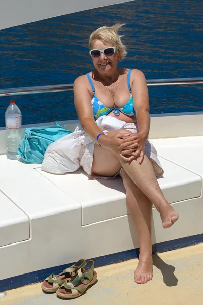 Senior woman on the yacht deck on sea water background.