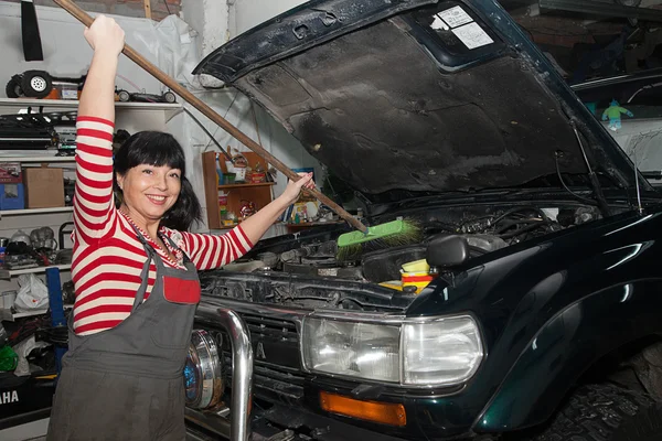 Smiling woman washing her car in the garage