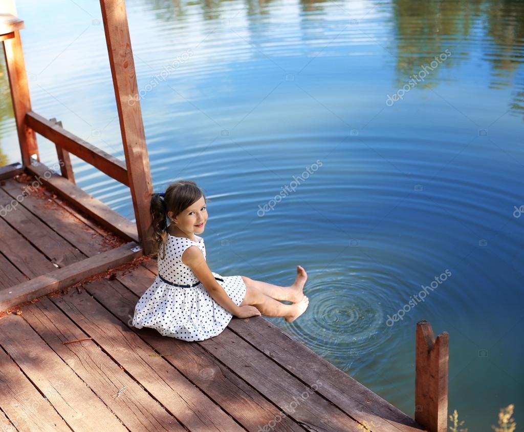 Голенькая милашка сидит на деревянном помосте