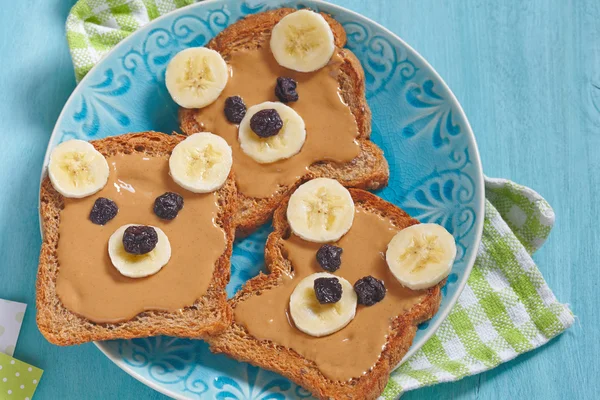 Funny bear face sandwich with peanut butter, banana and raisins