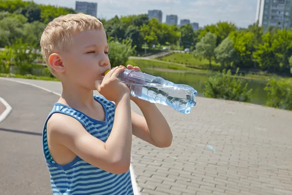 Child drinking pure water in a park