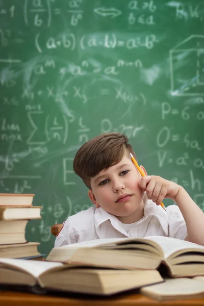 Thinking schoolboy looking at his dream on blackboard