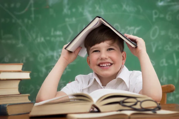 Happy little boy, pupil with book on head
