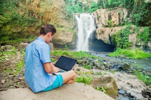 Man using his laptop in a jungle