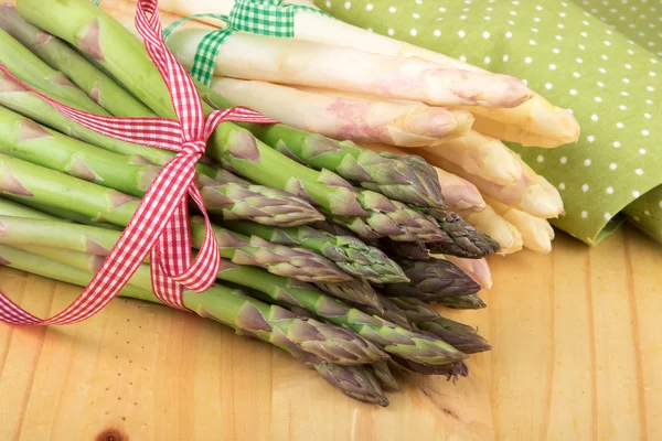 Green and white asparagus on wooden table in closeup. Vegan food, vegetarian and healthy cooking concept.