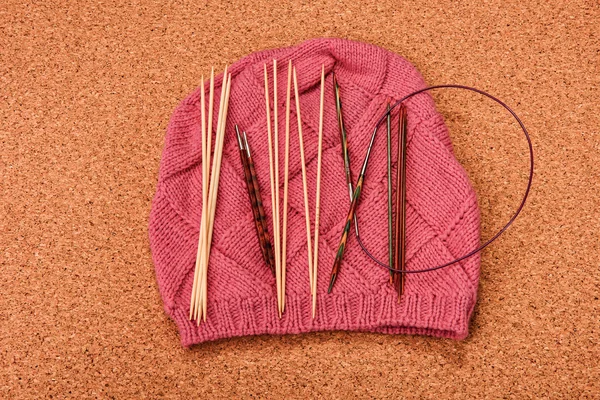 The composition of a hat and wooden knitting needles