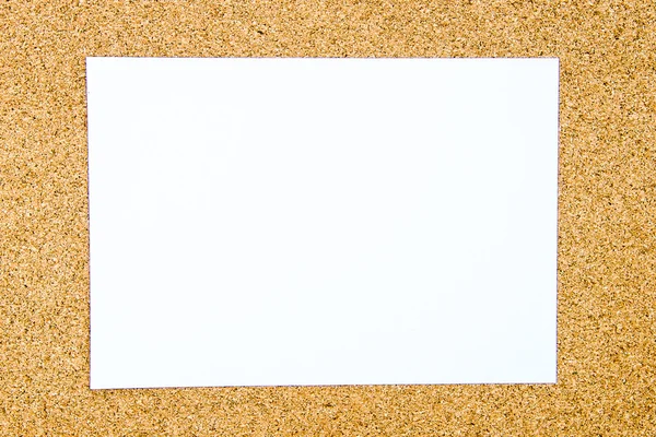 Blank white paper note over cork board background