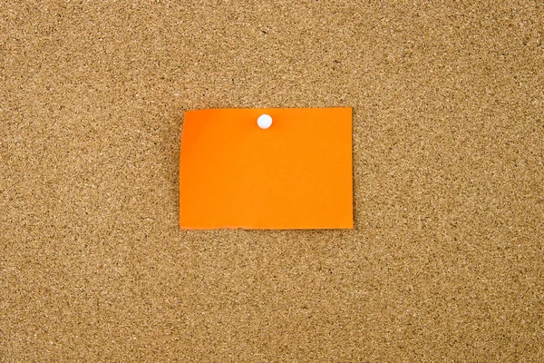 Blank orange paper note pinned on cork board