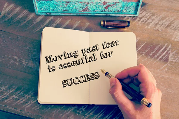 Motivational message MOVING PAST FEAR IS ESSENTIAL TO SUCCESS written on notebook