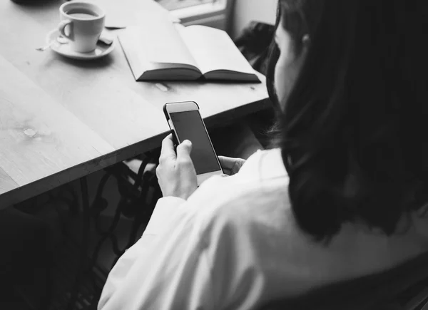 Woman sits in a cafe with a cup of coffee, tea. Read a book and dream. Looking at mobile phone. Wait for somebody