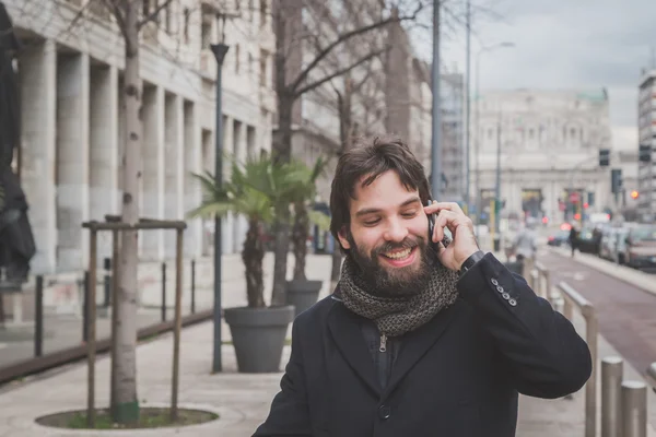 Young handsome bearded man talking on phone
