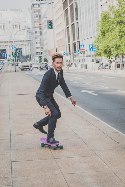 Young handsome Asian model riding his skateboard