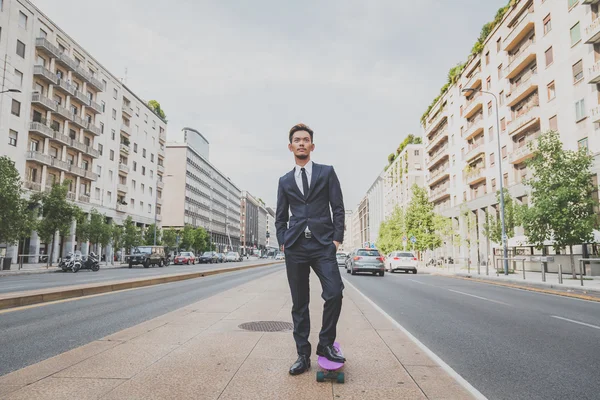 Young handsome Asian model posing with his skateboard