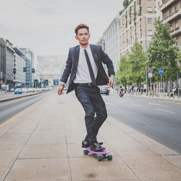 Young handsome Asian model riding his skateboard