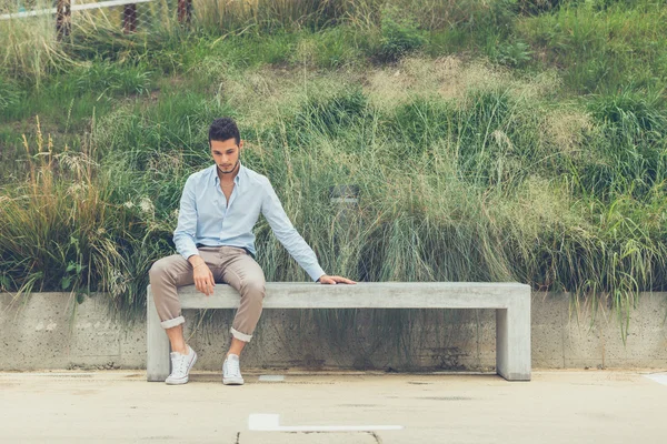 Young handsome man sitting on a concrete bench