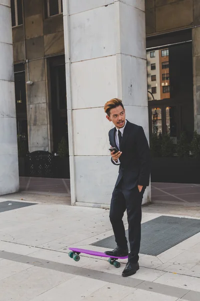 Young handsome Asian model posing with his skateboard