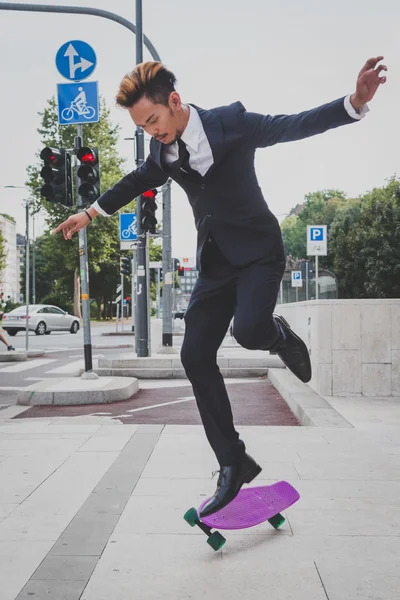 Young handsome Asian model jumping with his skateboard