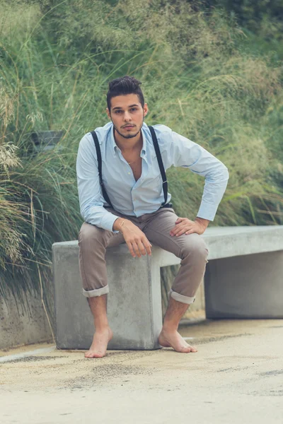 Young handsome man sitting on a concrete bench