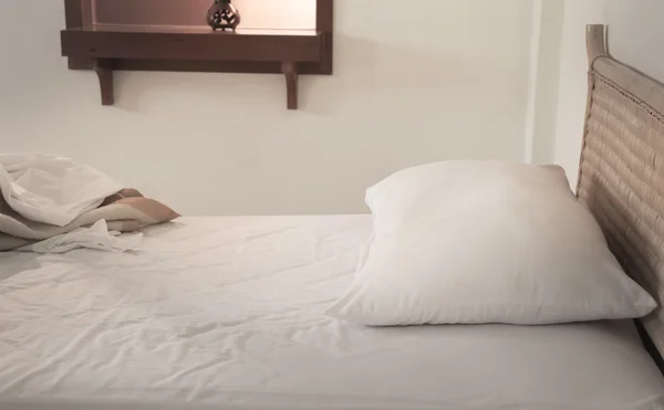 An unmade bed with white linens