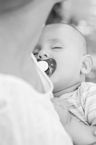 Sleeping baby with a pacifier in mother\'s