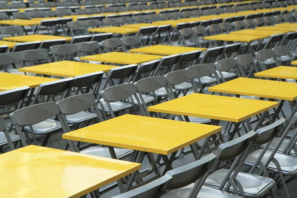 Rows of yellow metal tables and chairs