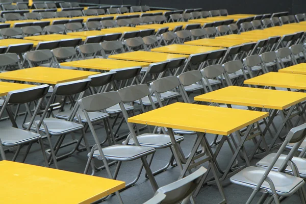 Rows of yellow metal tables and chairs