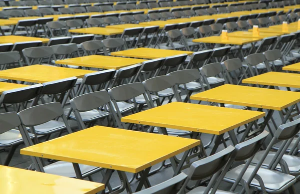 Rows of yellow metal tables and chairs