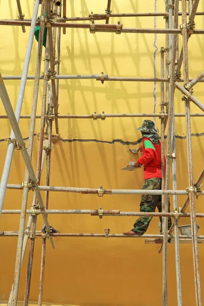 Worker working during renovation of large buddha statue at Wat Muang, Thailand.