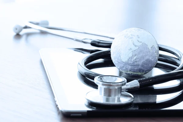 Studio macro of a stethoscope and texture globe with digital tab