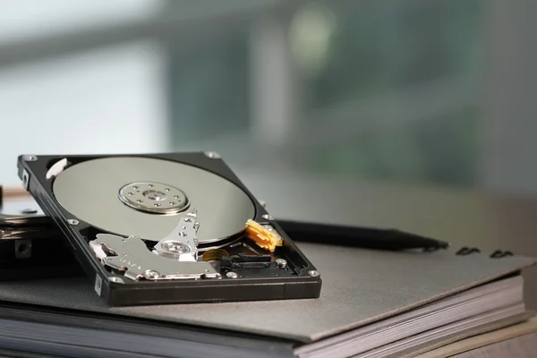 Close up of open computer hard disk drive on desk and notebook