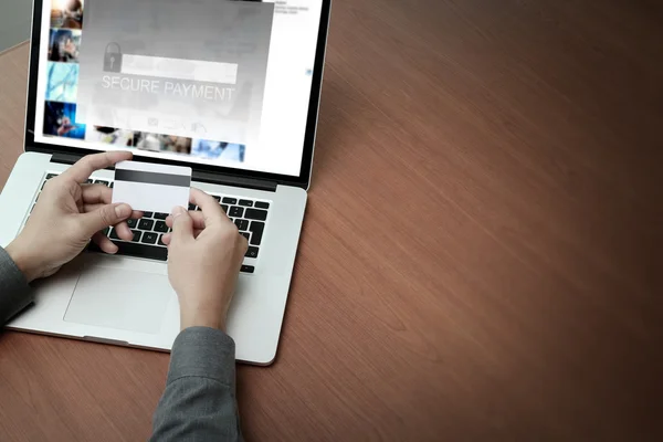 Top view of hands using laptop and holding credit card with blan