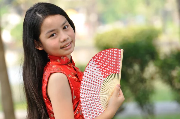 Asia female teenager wear red suit and hold a paper fan in garde