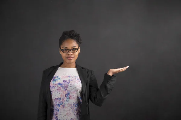 African woman holding hand out on blackboard background