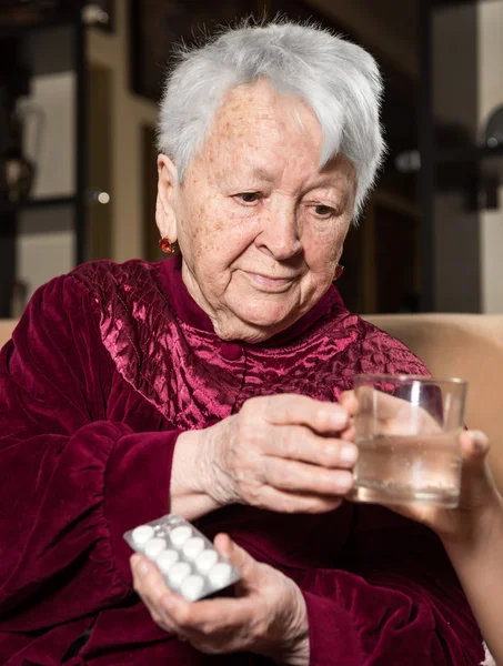 Girl giving a glass of water to the sick old woman