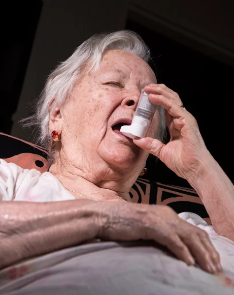 Old sick woman with asthma inhaler