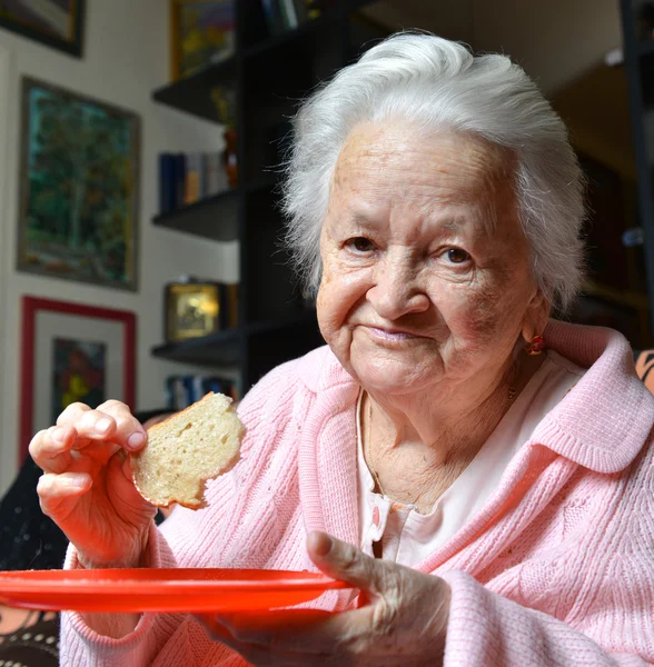 Old woman eating a slice of  bread
