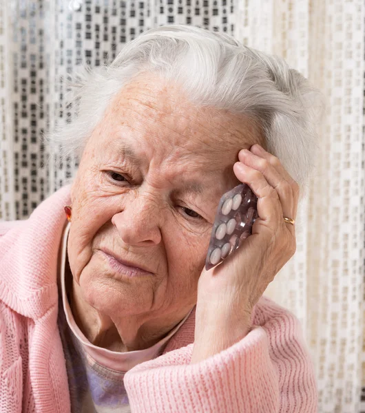 Old sad woman holding pills