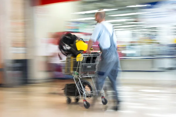 Worker in overalls pushing trolley in hardware shop