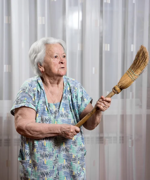 Old angry woman threatening with a broom