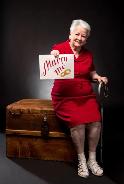 Old woman holding Marry Me board