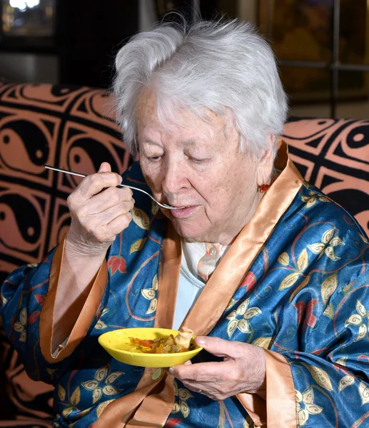 Old woman eating at home