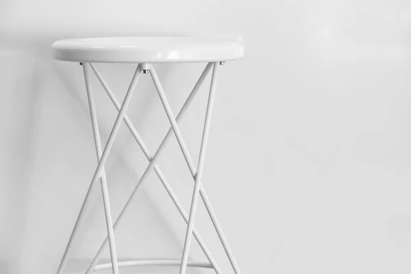 White metallic stool over a white wall. Copy space