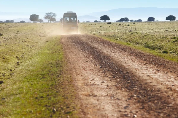 Dirty road in a mediterranean meadow with minibus. Cabeneros. Sp