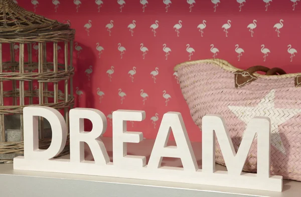 Dream wooden text over a shelf with pink background