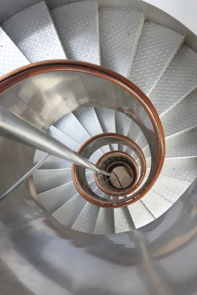 Metallic spiral stair with wooden handrails inside a lighthouse