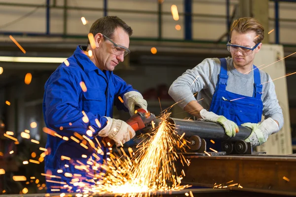 Two workers working with angle grinder