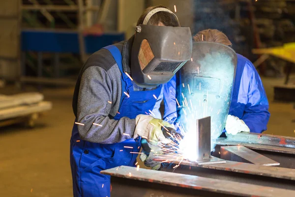 Two steel construction workers welding metal