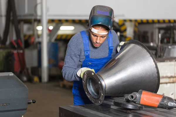 Welder inspecting  metal piece for quality control