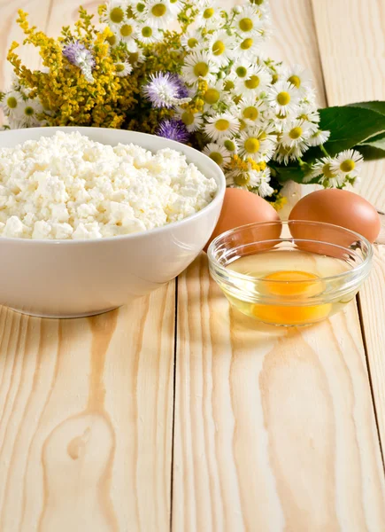 Cottage cheese and eggs on the meadow flowers background