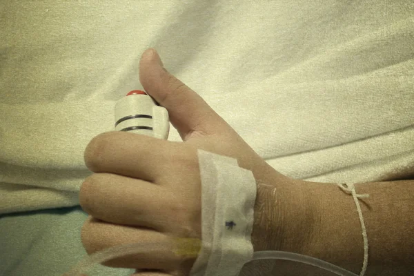 The hand of a patient in hospital holding a help or assist call